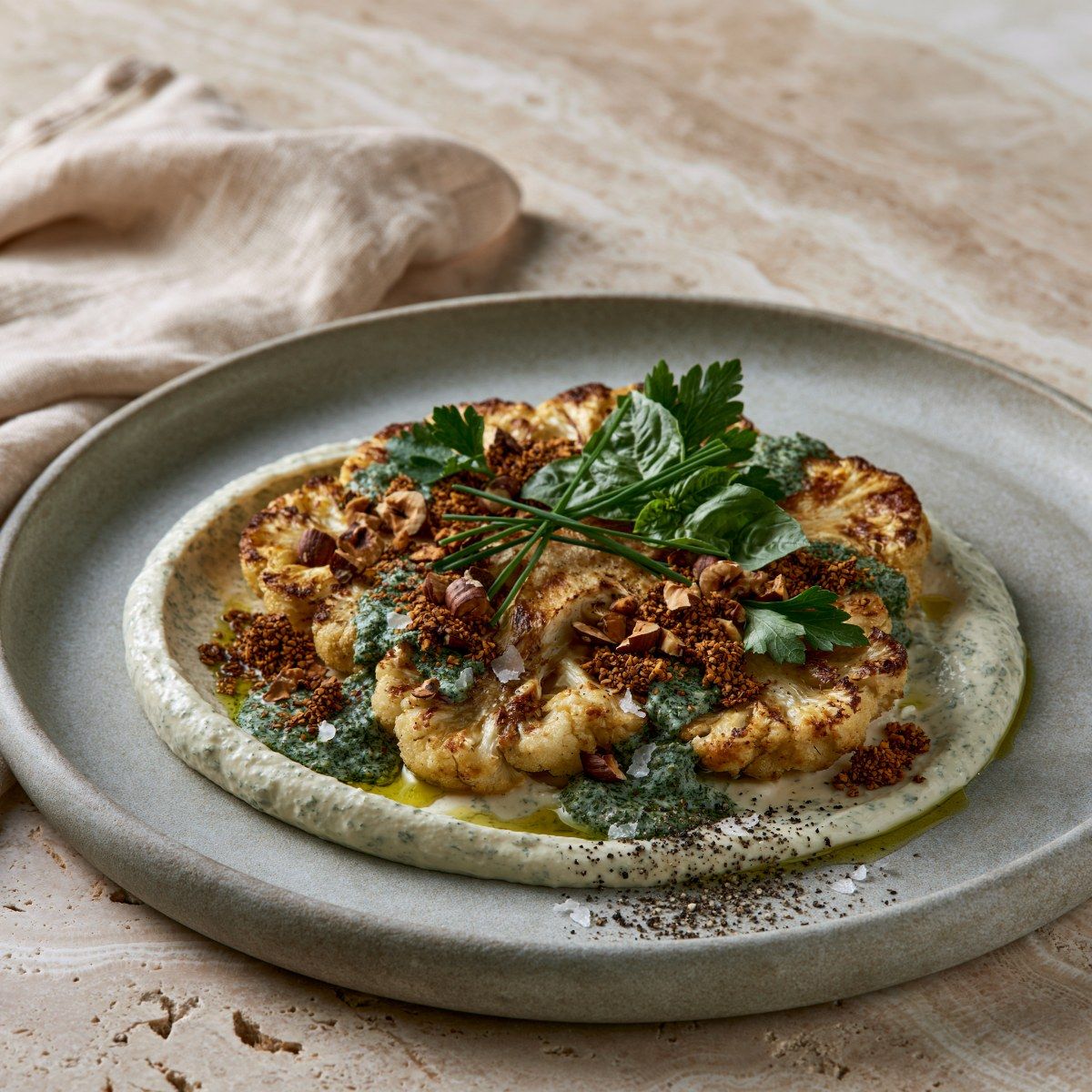 Bloemkoolsteak met romige kruidenlabneh, hazelnoten & groene kruidenolie